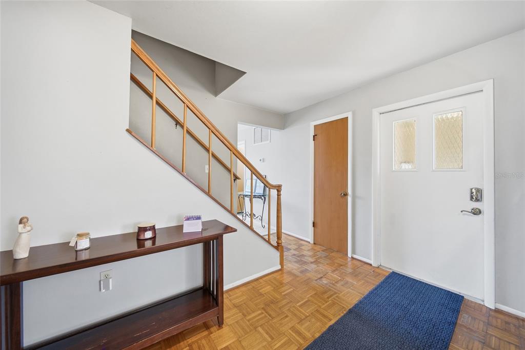 An entryway features a wooden staircase, parquet flooring, a console table, and a white door — 5315 9TH AVENUE DRIVE W, BRADENTON, FL