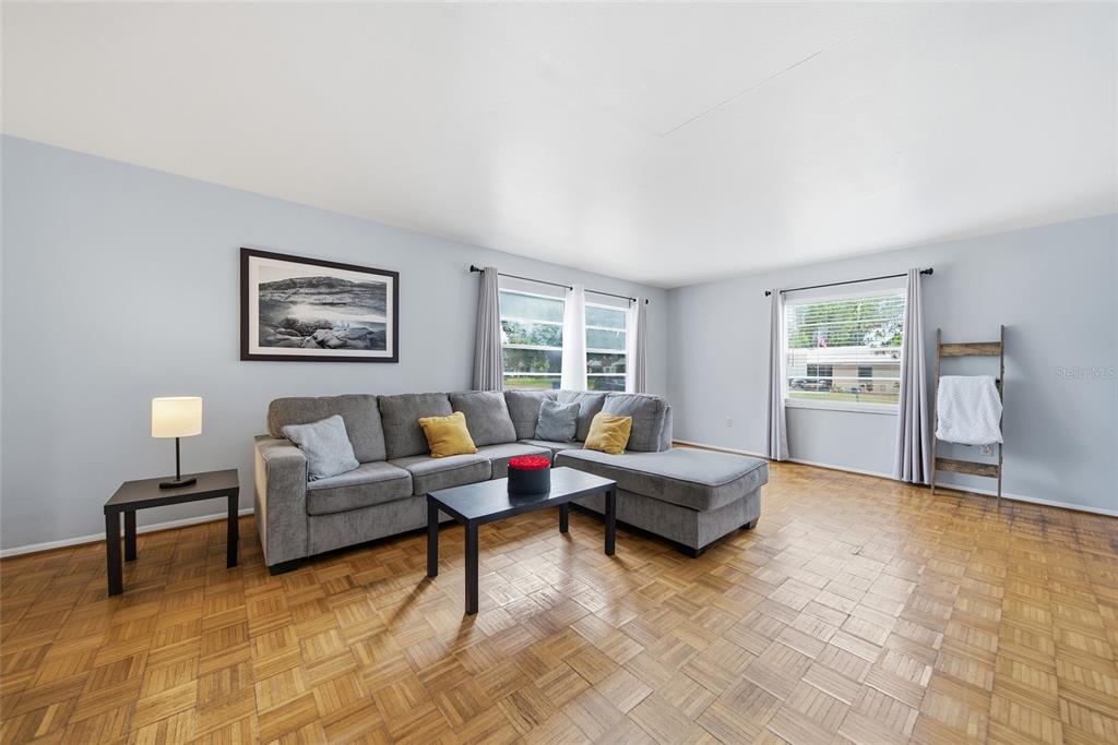 A living room features a gray sectional sofa, a coffee table, and parquet wood flooring — 5315 9TH AVENUE DRIVE W, BRADENTON, FL
