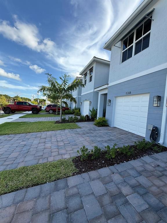 A row of light blue townhouses with white garage doors and paved driveways under a sky — 142 NE 14TH TERRACE, HOMESTEAD, FL
