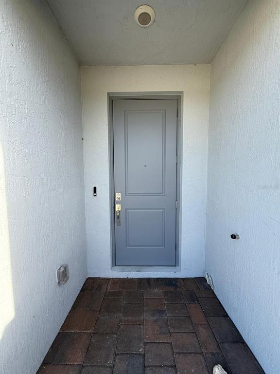 A gray front door is centered in a covered entryway with paver flooring — 142 NE 14TH TERRACE, HOMESTEAD, FL