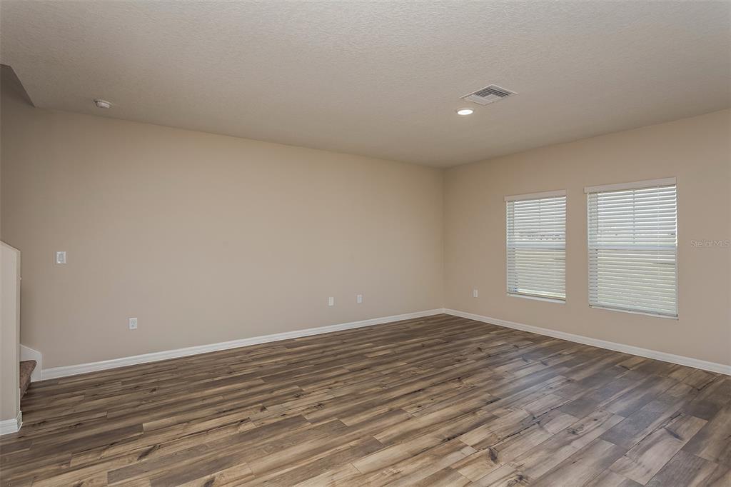 An empty room with light-colored walls, wood-look flooring, and two windows with blinds — 1731 VANILLA STREET, LAKE HAMILTON, FL