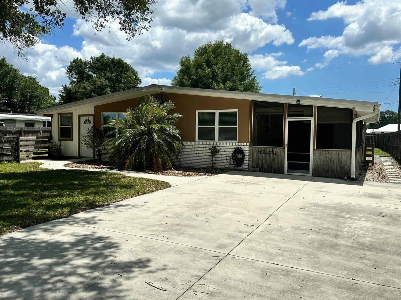 A single-story house with a brown exterior, white brick base, and a screened-in porch — 1005 NW 5th Street, Okeechobee FL 34972, OKEECHOBEE, FL