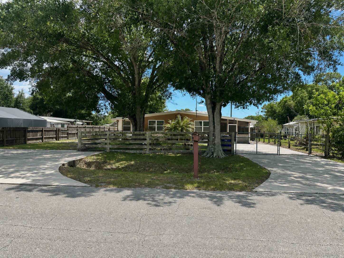 A single-story house with a wooden fence and two large trees in the front yard — 1005 NW 5th Street, Okeechobee FL 34972, OKEECHOBEE, FL