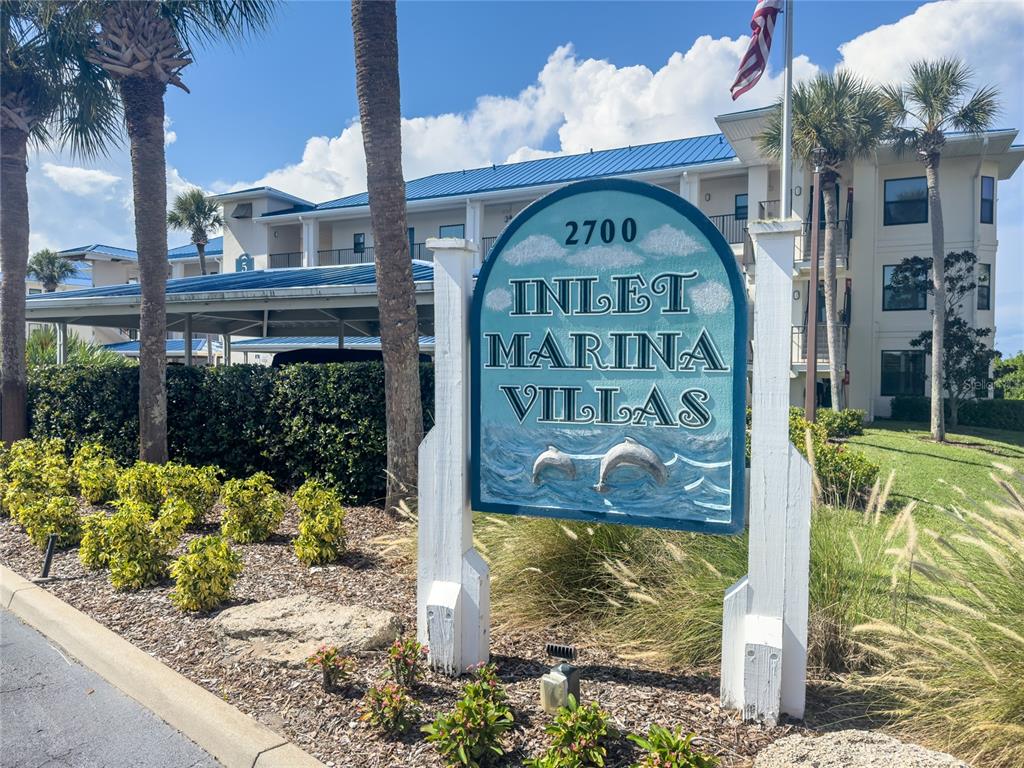 A sign for Inlet Marina Villas stands in front of a multi-story residential building — 2700 N PENINSULA AVENUE UNIT 516, NEW SMYRNA BEACH, FL