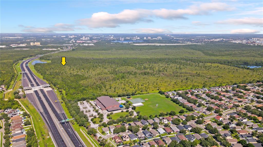An aerial view shows a large wooded lot next to a highway and residential neighborhood — Vacant Land on INTERNATIONAL DRIVE S, ORLANDO, FL