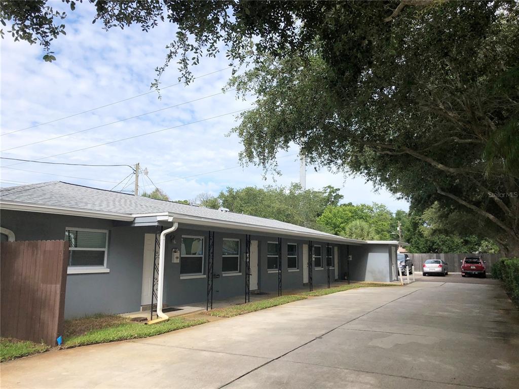 A single-story gray apartment building with a concrete driveway and mature trees — 520 70TH STREET N UNIT 2, ST PETERSBURG, FL