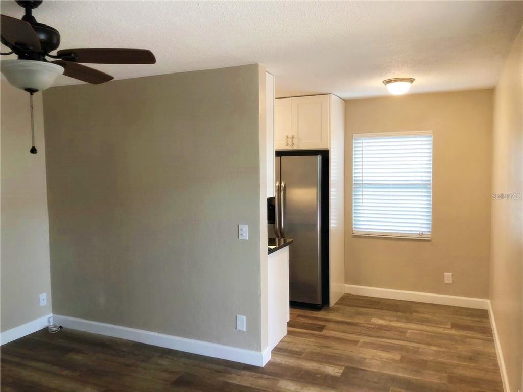 A kitchen with stainless steel appliances and white cabinets opens into a dining area — 520 70TH STREET N UNIT 2, ST PETERSBURG, FL