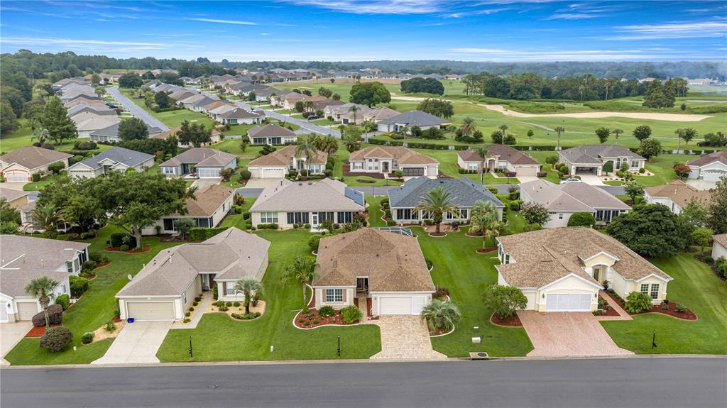 An aerial view shows a suburban neighborhood with single-family homes, manicured lawns, and a golf course — 12503 SE 94TH COURT, SUMMERFIELD, FL