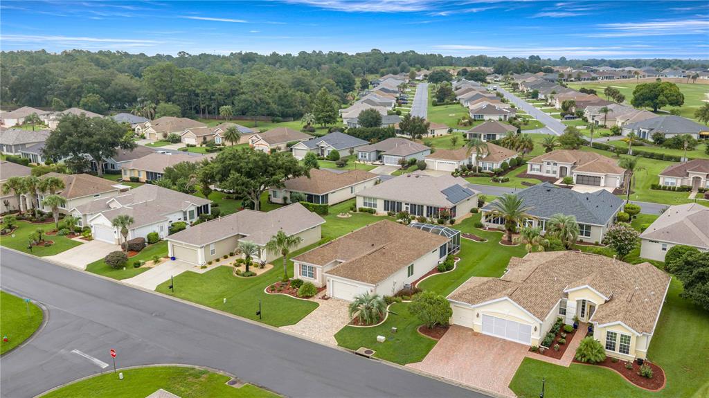 An aerial view shows a suburban neighborhood with single-family homes, paved streets, and green lawns — 12503 SE 94TH COURT, SUMMERFIELD, FL