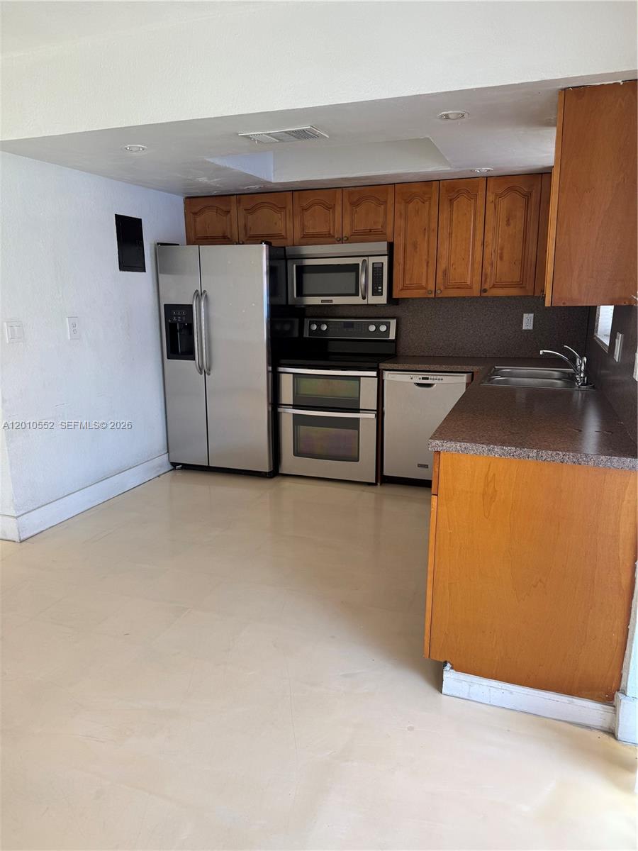 This kitchen features wooden cabinets, stainless steel appliances, and a dark speckled countertop — 5231 NW 27th St # 8A, Lauderhill FL 33313, LAUDERHILL, FL