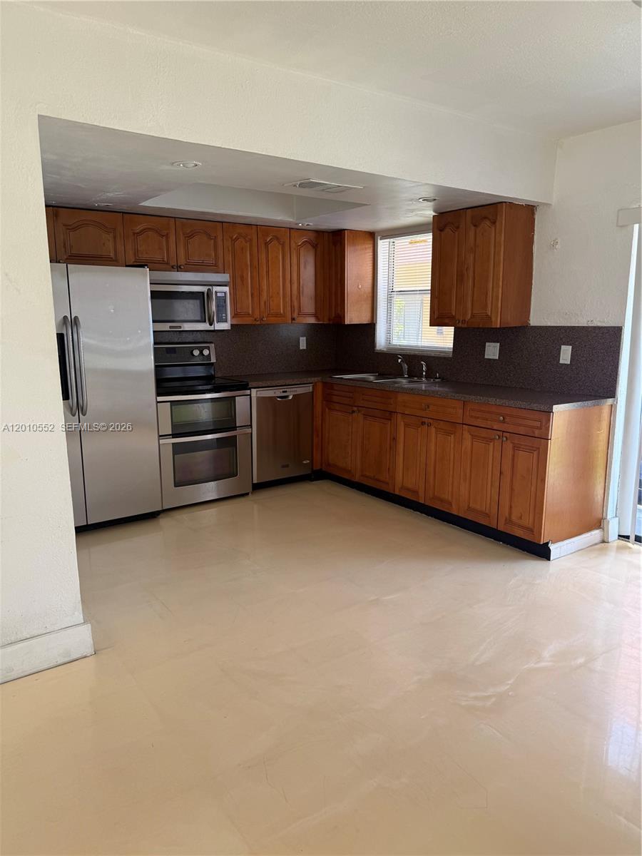 A kitchen features wooden cabinets, stainless steel appliances, and light-colored tile flooring — 5231 NW 27th St # 8A, Lauderhill FL 33313, LAUDERHILL, FL