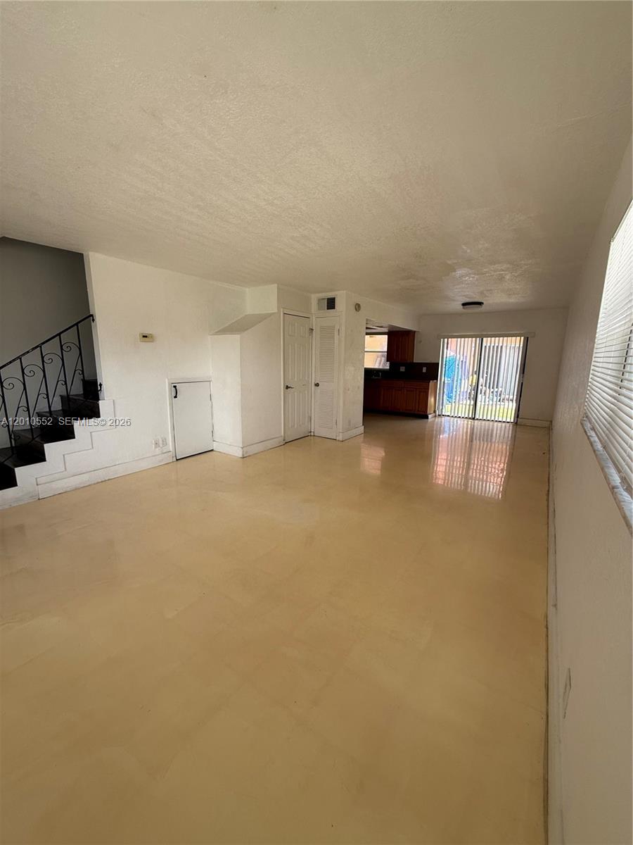 An open-concept living area features light-colored tile flooring, a staircase with a railing, and a kitchen — 5231 NW 27th St # 8A, Lauderhill FL 33313, LAUDERHILL, FL