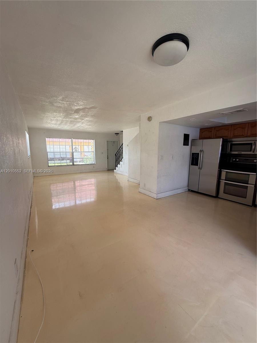 An open-concept living area features light-colored tile flooring, white walls, and an adjacent kitchen — 5231 NW 27th St # 8A, Lauderhill FL 33313, LAUDERHILL, FL