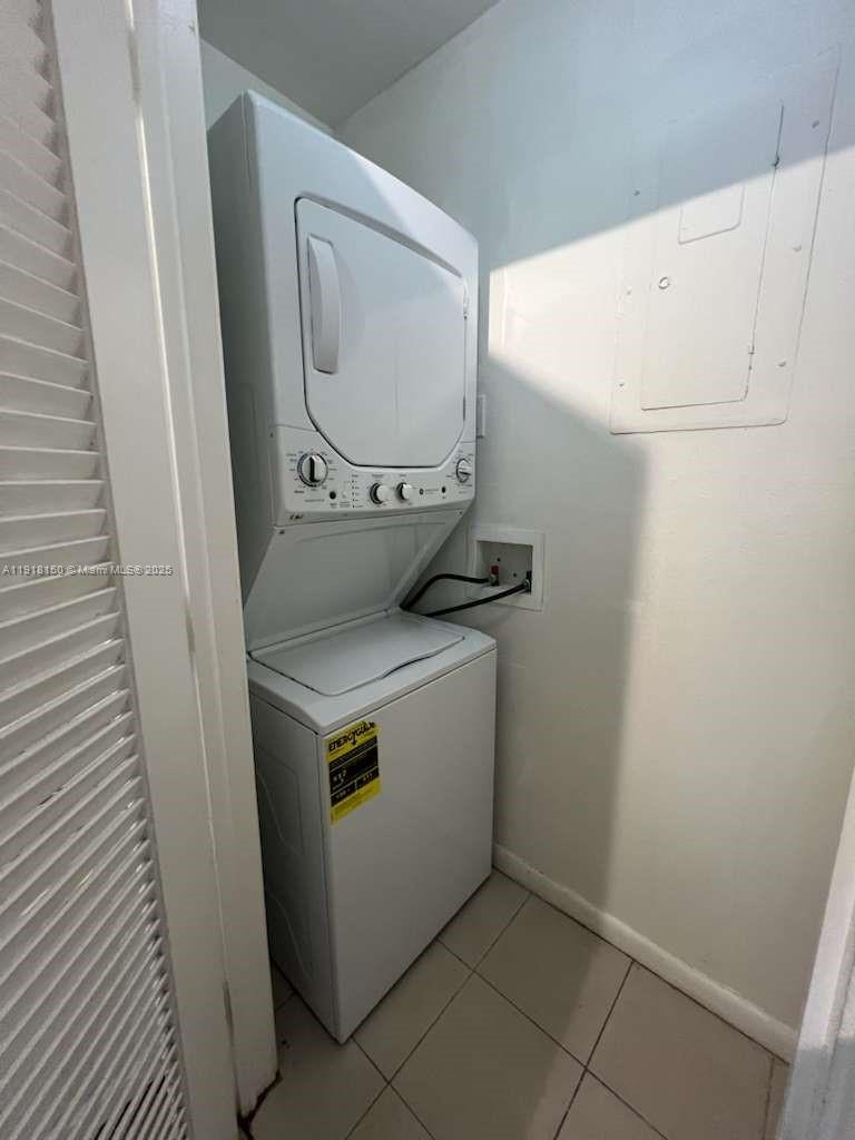 A white stacked washer and dryer unit sits inside a small tiled laundry closet — 721 SE 1st Way # B18, Deerfield Beach FL 33441, DEERFIELD BEACH, FL