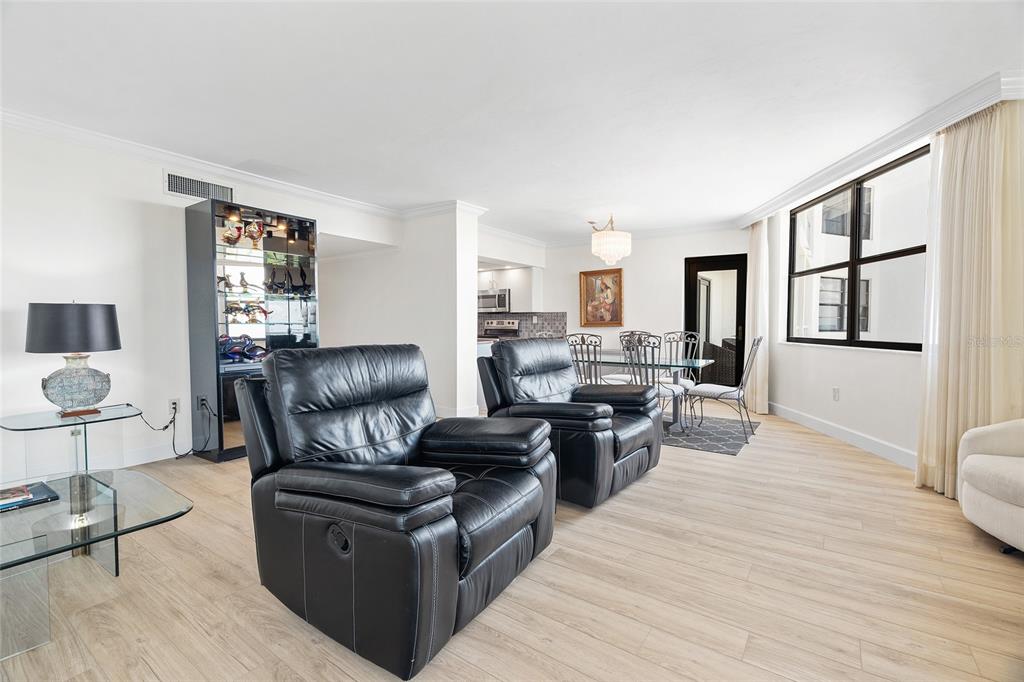A living room with two black leather recliners, light wood flooring, and a dining area — 1000 LONGBOAT CLUB ROAD, LONGBOAT KEY, FL