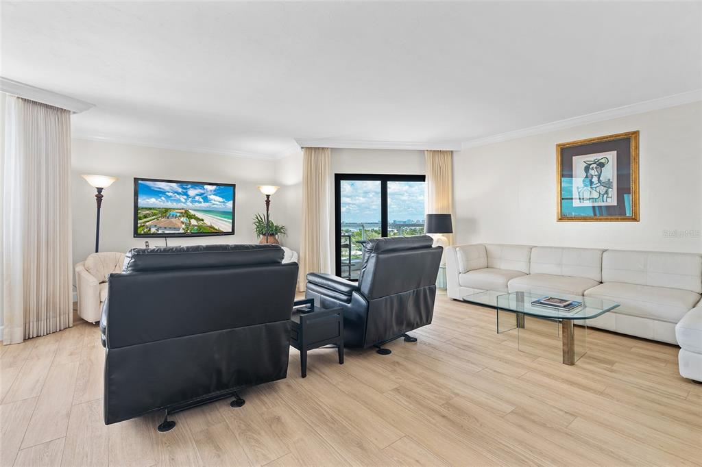 A living room features light wood flooring, a white sectional sofa, and two black recliners — 1000 LONGBOAT CLUB ROAD, LONGBOAT KEY, FL