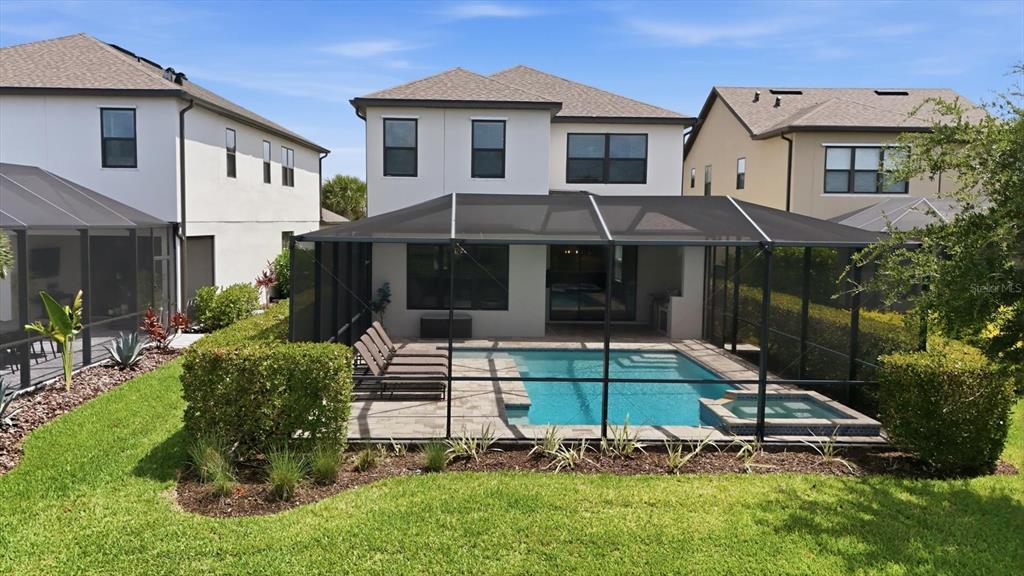 A two-story house features a screened-in pool and spa with a patio and lounge chairs — 8212 SHOOTING STAR RD, SARASOTA, FL