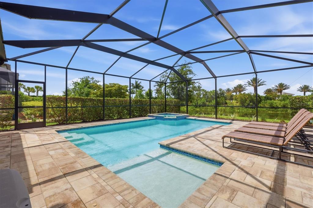 A screened-in swimming pool and spa with lounge chairs on a paved patio deck — 8212 SHOOTING STAR RD, SARASOTA, FL