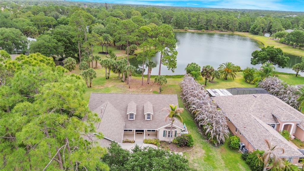 An aerial view of a suburban house with a shingled roof near a lake — 255 BRIGHTWATER DRIVE SE, PALM BAY, FL