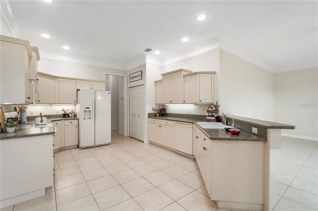 A kitchen features light-colored cabinets, dark countertops, a white refrigerator, and tiled flooring — 255 BRIGHTWATER DRIVE SE, PALM BAY, FL