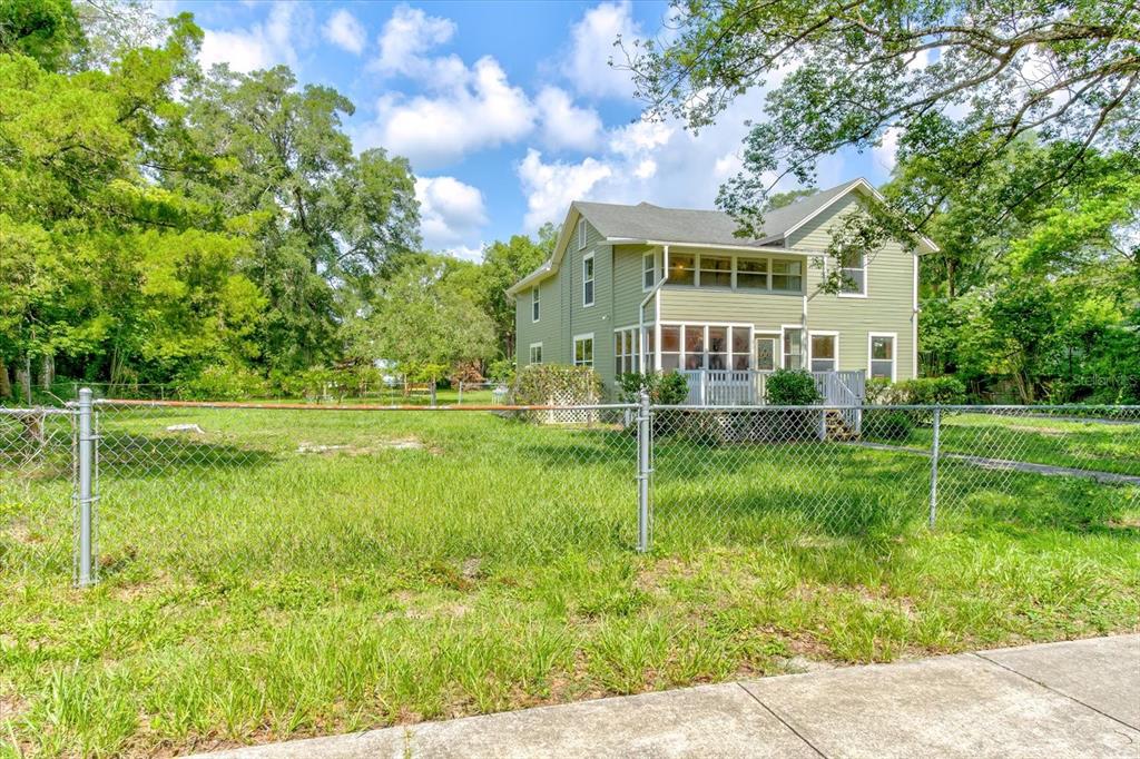 A two-story green house stands behind a chain-link fence in a grassy yard — 543 N THORPE AVENUE, ORANGE CITY, FL