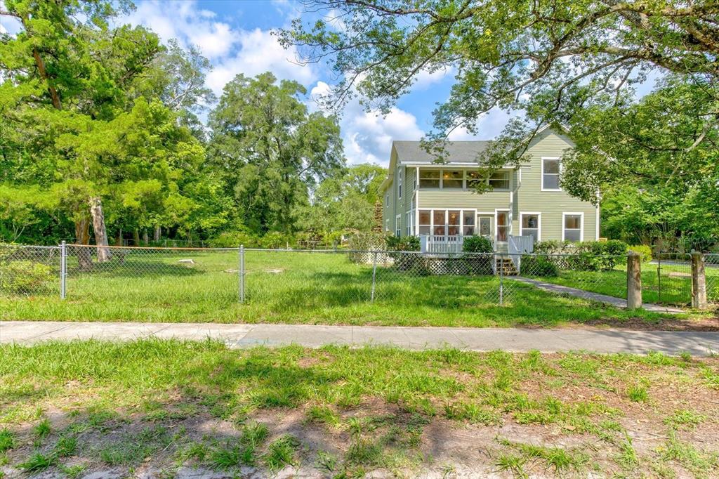 A two-story light green house sits behind a chain-link fence and a grassy yard — 543 N THORPE AVENUE, ORANGE CITY, FL