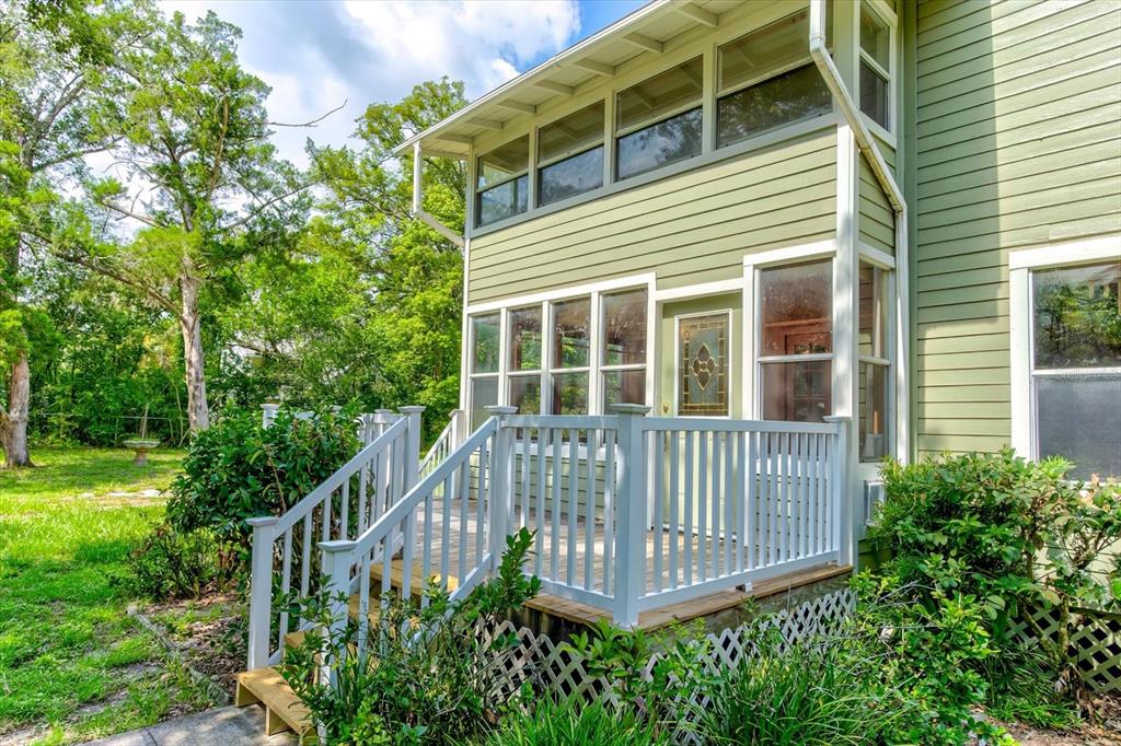 A two-story house exterior features light green siding, a white wooden deck, and large windows — 543 N THORPE AVENUE, ORANGE CITY, FL