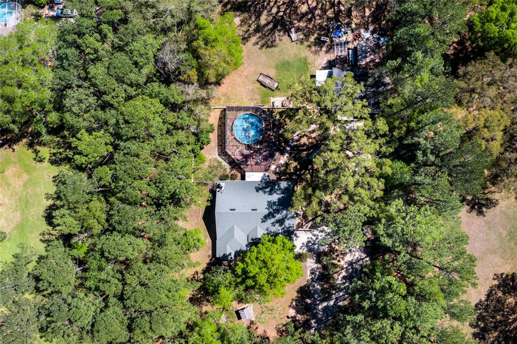 An aerial view shows a house with a screened pool surrounded by dense woods — 7615 NW 176TH STREET, ALACHUA, FL
