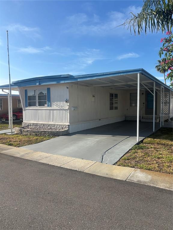 A single-story mobile home with a carport and a stone-accented front planter — 7901 40TH AVENUE N UNIT 60, ST PETERSBURG, FL