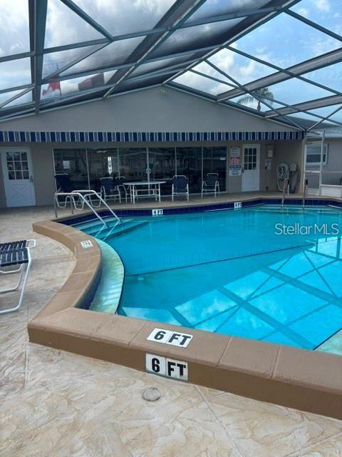 A screened-in swimming pool with a six-foot depth marker sits beside a building — 7901 40TH AVENUE N UNIT 60, ST PETERSBURG, FL
