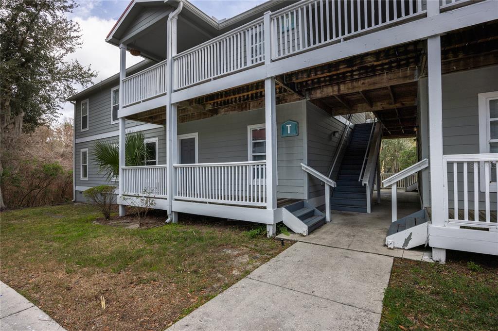 A two-story apartment building exterior features gray siding, white railings, and an outdoor staircase — 2905 SW ARCHER ROAD UNIT S4024, GAINESVILLE, FL