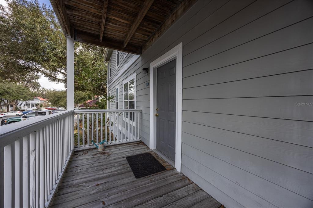 A gray wooden exterior door opens onto a covered balcony with a white railing — 2905 SW ARCHER ROAD UNIT S4024, GAINESVILLE, FL