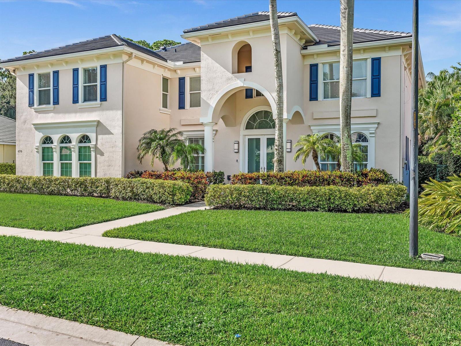 A two-story stucco house with blue shutters, an arched entryway, and a manicured front lawn — 4770 Glenn Pine Lane, Boynton Beach FL 33436, BOYNTON BEACH, FL