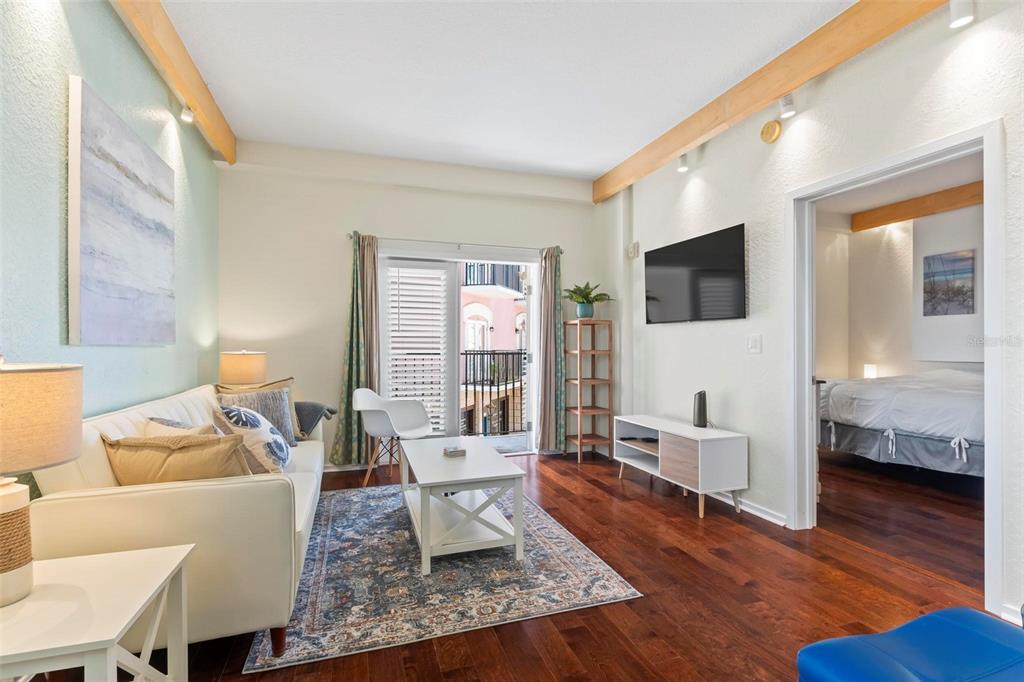 A living room with hardwood floors, a white sofa, and a doorway leading to a bedroom — 101 PALM HARBOR PARKWAY UNIT A212, PALM COAST, FL