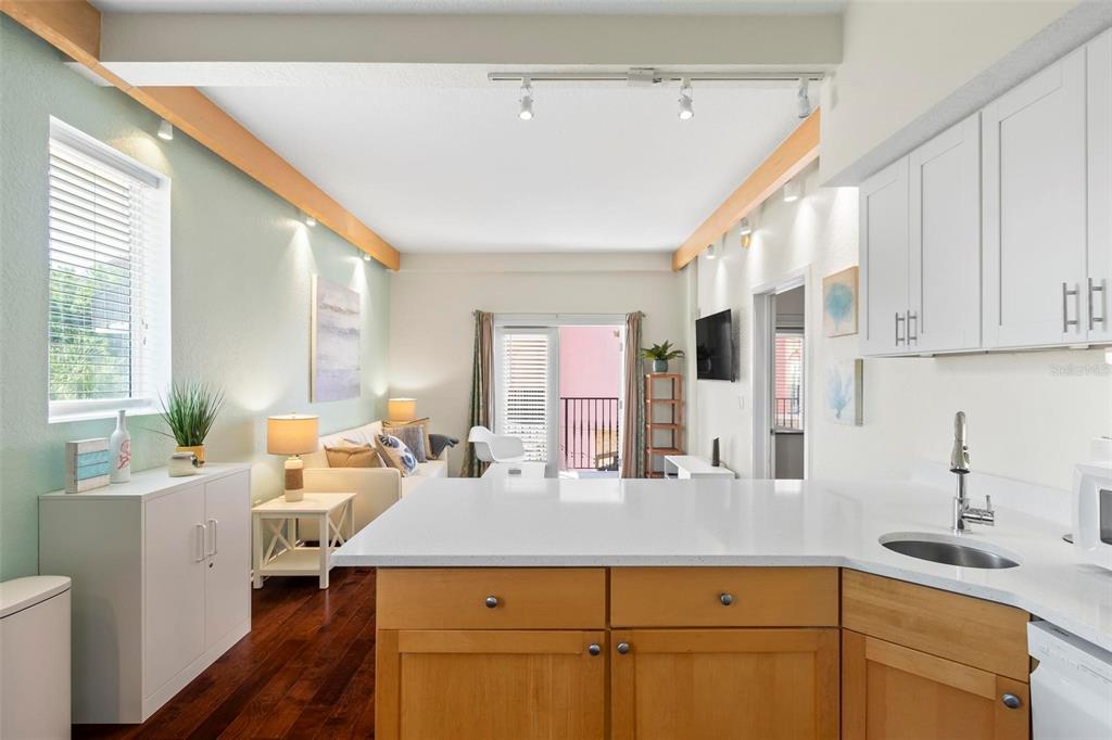 A kitchen with white countertops and wood cabinets overlooks a living area with hardwood floors — 101 PALM HARBOR PARKWAY UNIT A212, PALM COAST, FL