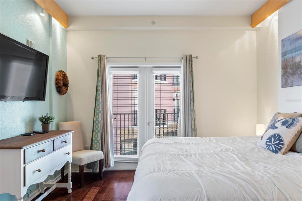 A bedroom features a white dresser, a bed, and French doors opening to a balcony — 101 PALM HARBOR PARKWAY UNIT A212, PALM COAST, FL
