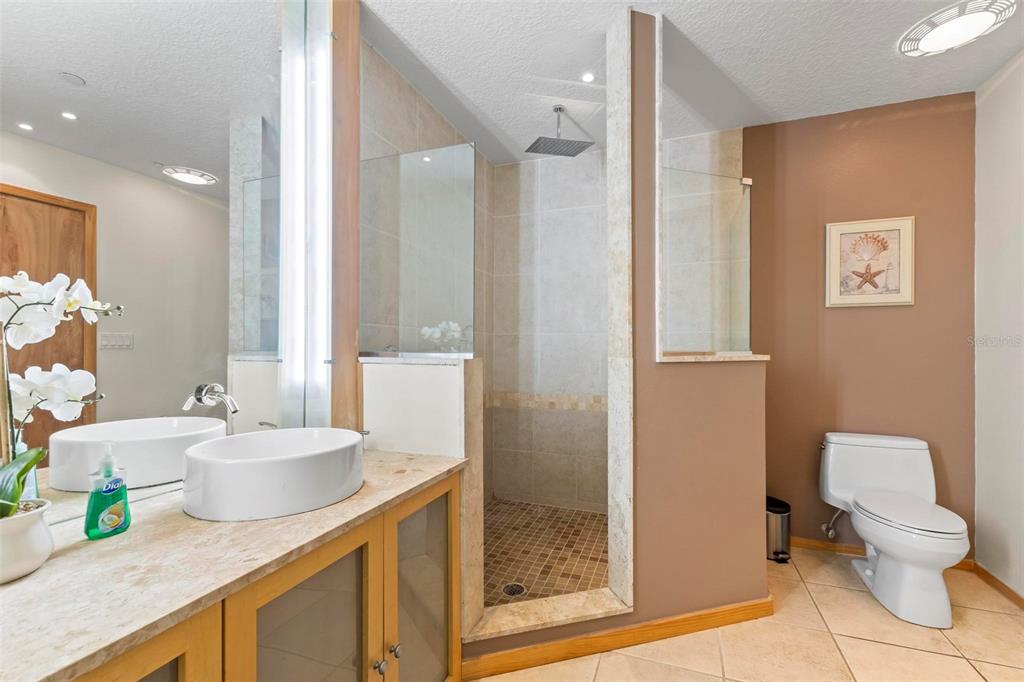 A bathroom features a double vanity, a walk-in tiled shower, and a toilet — 101 PALM HARBOR PARKWAY UNIT A212, PALM COAST, FL