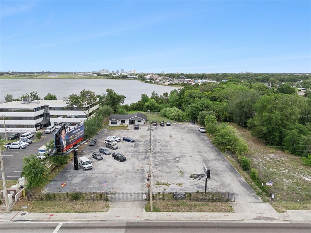 An aerial view shows a paved commercial lot with a small building and parked cars — 690 N SEMORAN BOULEVARD, ORLANDO, FL