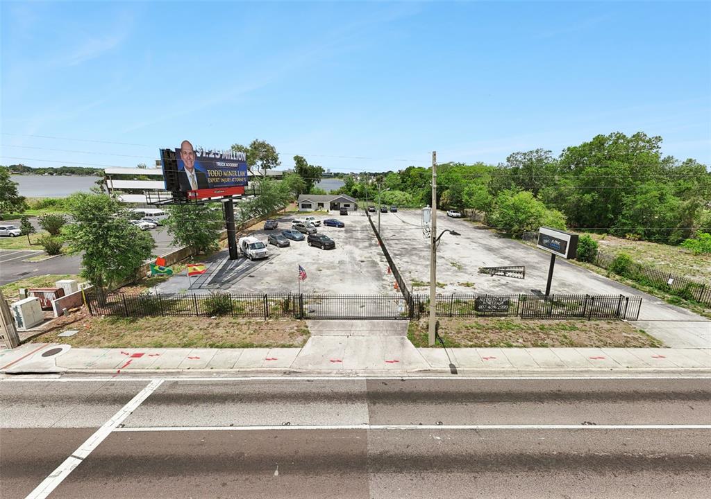 An aerial view shows a fenced, paved commercial lot with several parked vehicles and a billboard — 690 N SEMORAN BOULEVARD, ORLANDO, FL