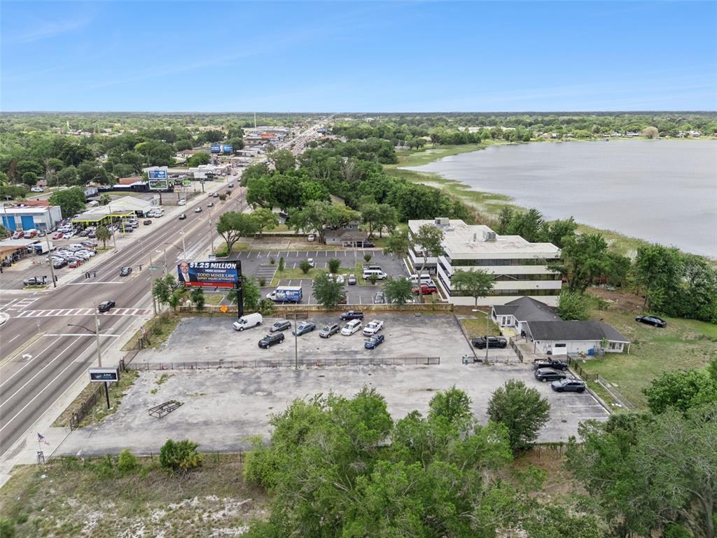 An aerial view shows a commercial building, a large parking lot, and a nearby lake — 690 N SEMORAN BOULEVARD, ORLANDO, FL