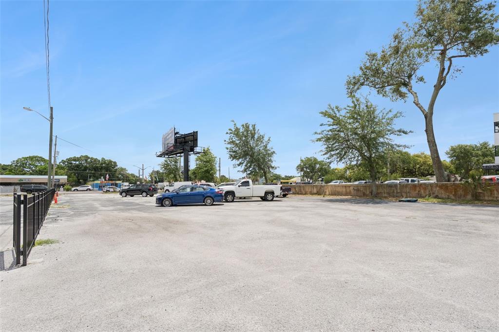 A large, paved outdoor parking lot with a few parked vehicles and a billboard — 690 N SEMORAN BOULEVARD, ORLANDO, FL