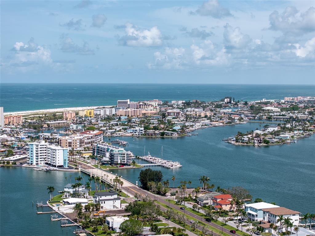 An aerial view shows a coastal town with a bridge, waterways, and sandy beaches — 2 PARADISE LANE, TREASURE ISLAND, FL