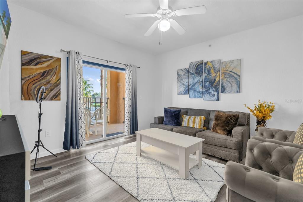 A living room features a gray sofa, a white coffee table, and a sliding glass door — 8112 POINCIANA BLVD UNIT 1214, ORLANDO, FL