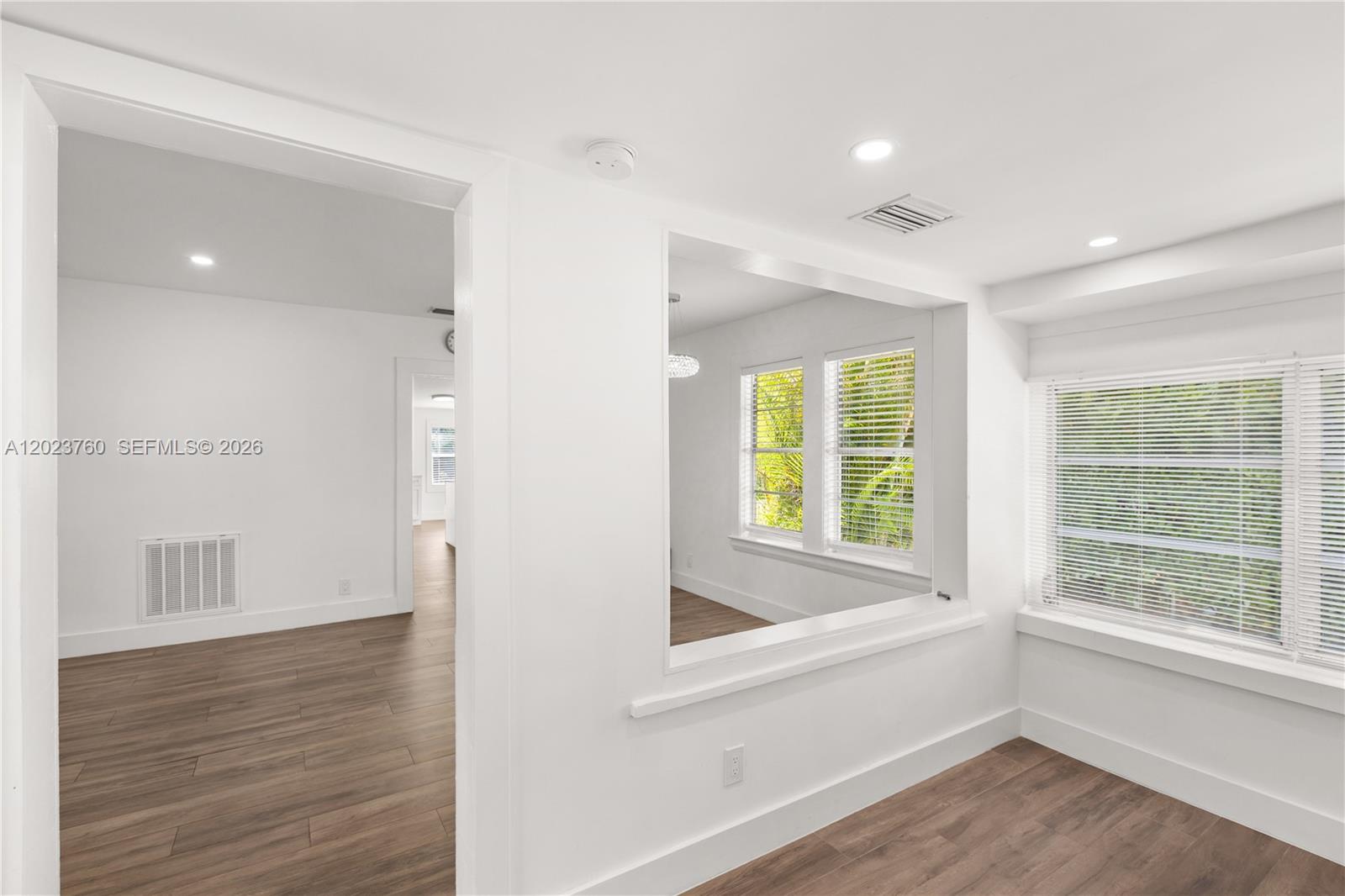 A bright room features white walls, wood-look flooring, and a large pass-through window — 900 Tangier St, Coral Gables FL 33134, CORAL GABLES, FL