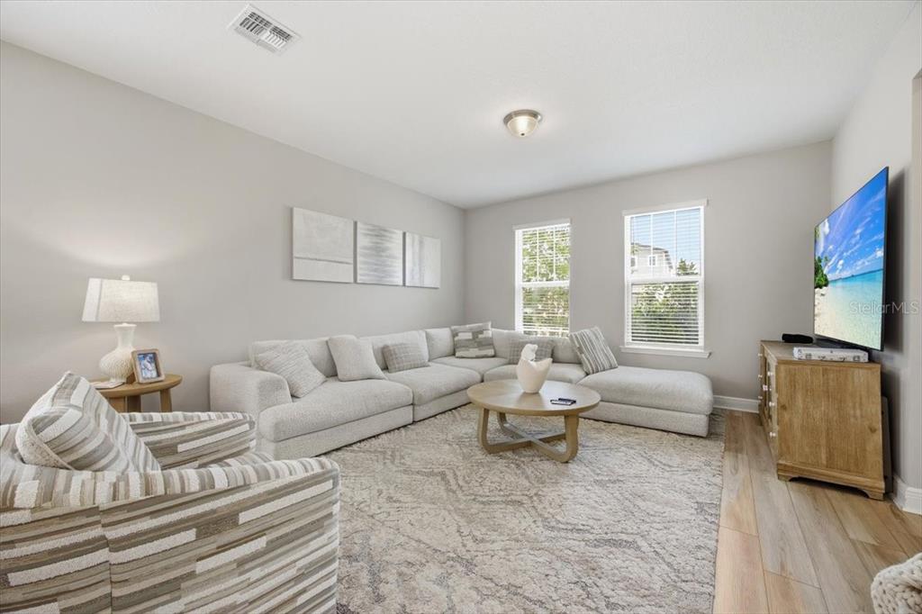 A living room features a large sectional sofa, a round coffee table, and a television — 12308 BRACCO STREET, WINTER GARDEN, FL