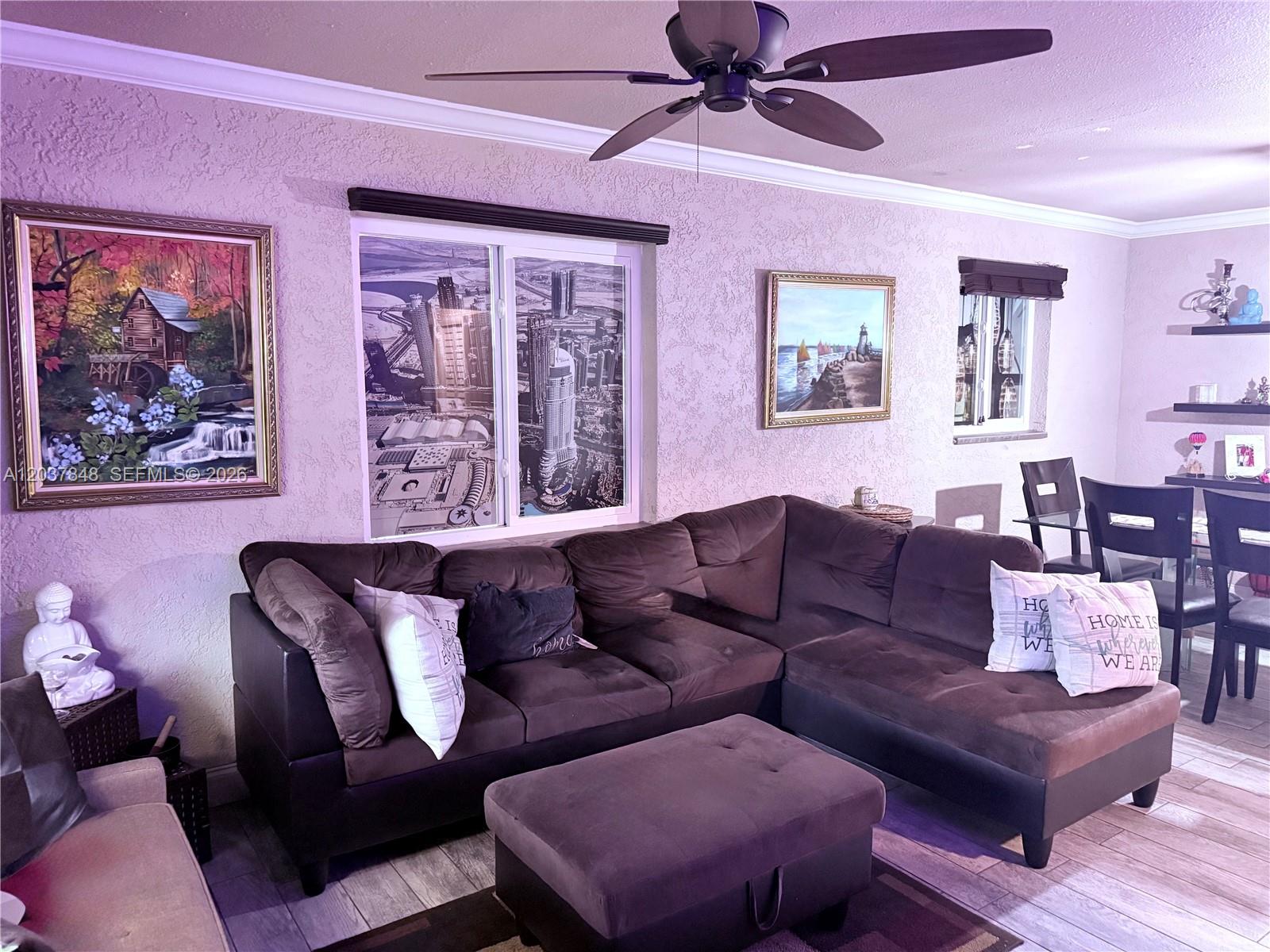 A living room features a brown sectional sofa, a matching ottoman, and wall-mounted artwork — 6424 Meade St, Hollywood FL 33024, HOLLYWOOD, FL