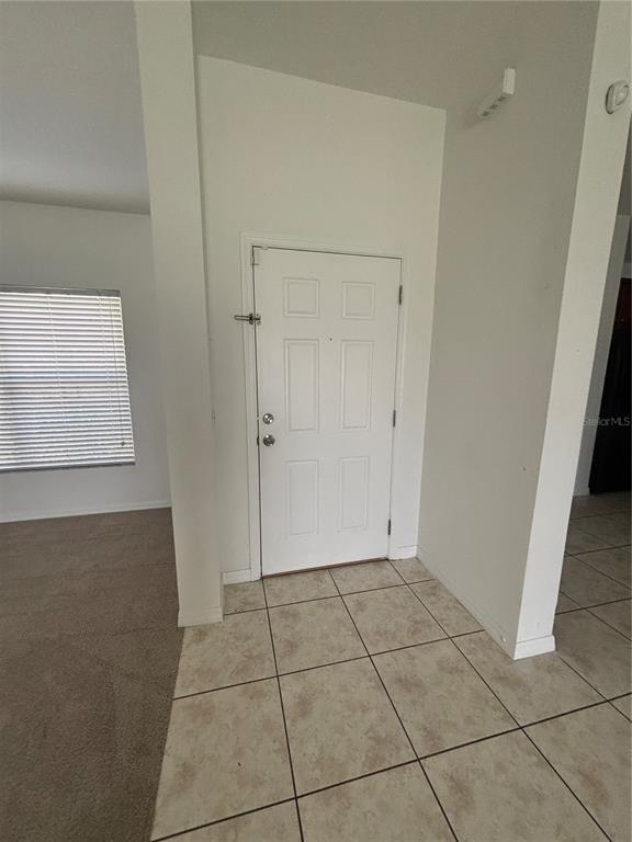 An entryway with a white door, tiled floor, and an adjacent carpeted room — 4030 MARINA ISLE DRIVE, KISSIMMEE, FL