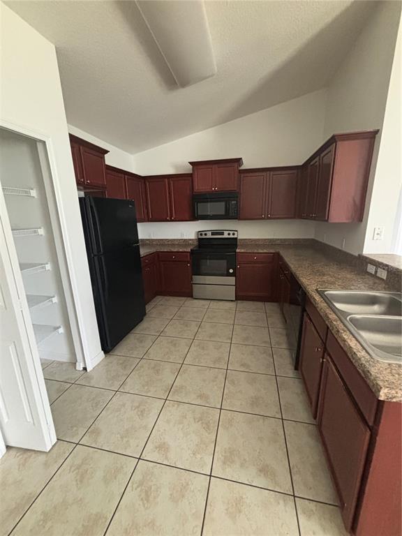 A kitchen features dark wood cabinets, black appliances, laminate countertops, and light-colored tile flooring — 4030 MARINA ISLE DRIVE, KISSIMMEE, FL