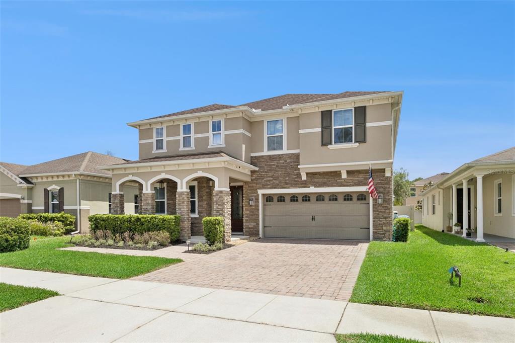 A two-story suburban house with a stone facade, beige stucco, and a two-car garage — 2331 AVELLINO AVENUE, ST CLOUD, FL