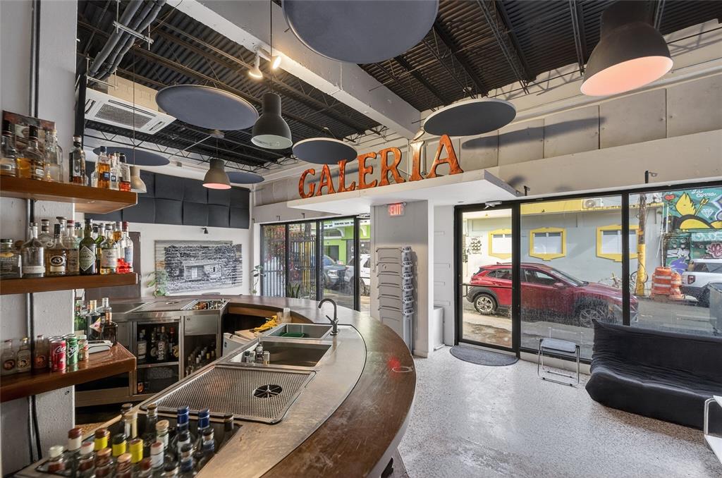 A bar area with a curved wooden counter, metal sink, and shelves stocked with liquor bottles — 722 CALLE CERRA, SAN JUAN, PR